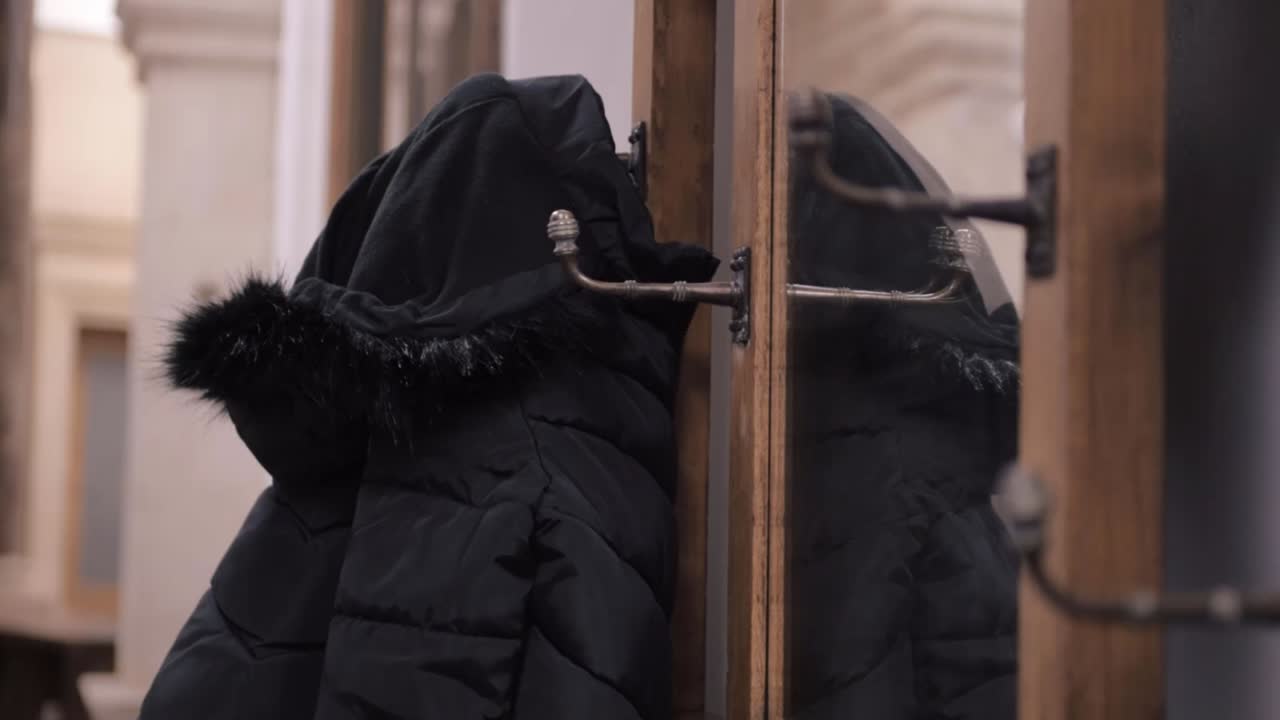 Woman gets her coat hanging on vintage ornate coat hanger hooks