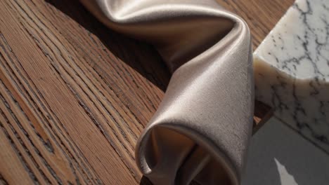 beige satin fabric drape on wooden surface with marble