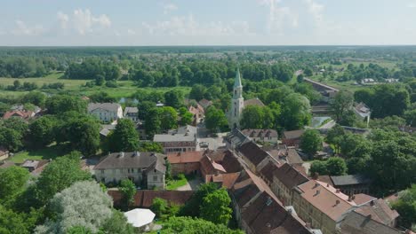 Aerial-establishing-view-of-Kuldiga-Old-Town-,-houses-with-red-roof-tiles,-Evangelical-Lutheran-Church-of-Saint-Catherine,-sunny-day,-travel-destination,-drone-shot-moving-forward