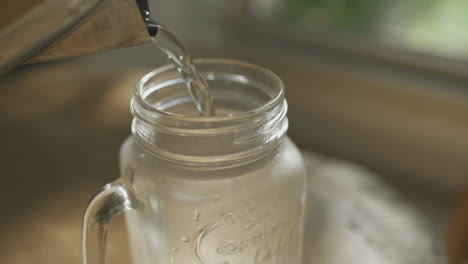 close up kettle pouring hot water into glass mug