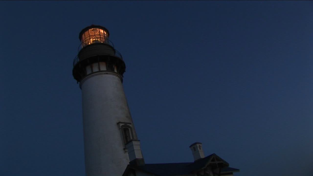 una vista de gusano de una torre de faro y un faro en la noche