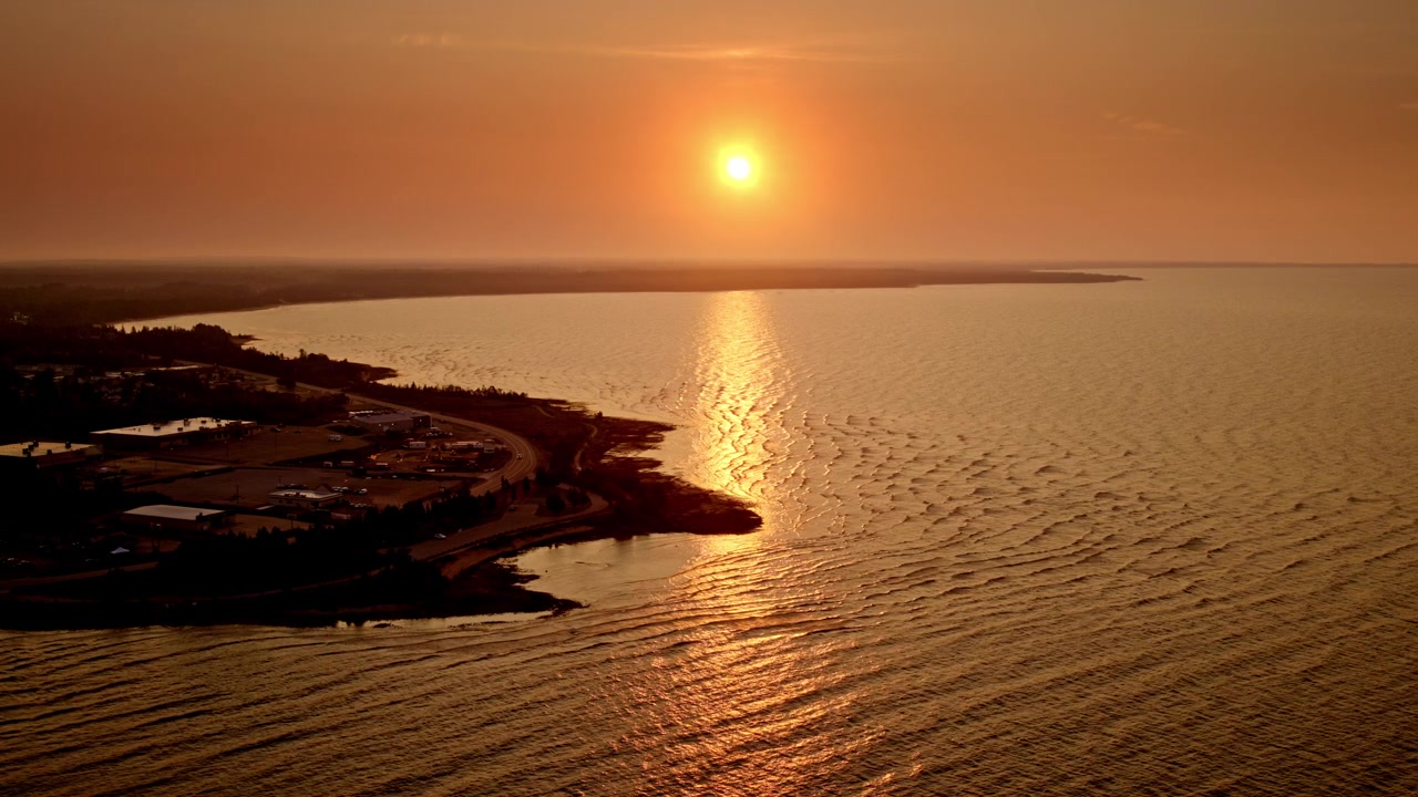 Tomada de drone voando sobre o Lago Michigan ao nascer do sol, com o Lago Michigan em primeiro plano.