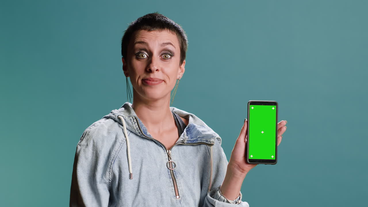Woman presenting a green screen mobile phone and giving thumbs up
