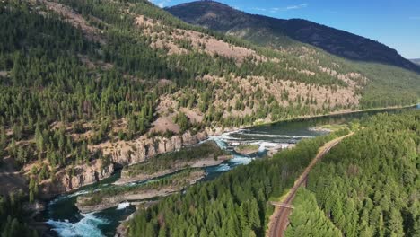 drone descending on the railway in dense forest along kootenai river in montana, north america