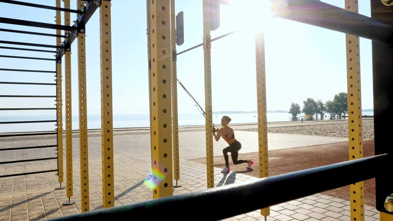 entrenamiento al aire libre. correas de suspensión. entrenamiento con correas. mujer joven atlética está haciendo ejercicios de resistencia de todo el cuerpo usando cuerdas en bucle trx, en la playa durante la puesta o el amanecer. entrenamiento de fitness al aire abierto. concepto de estilo de vida saludable. deporte matutino