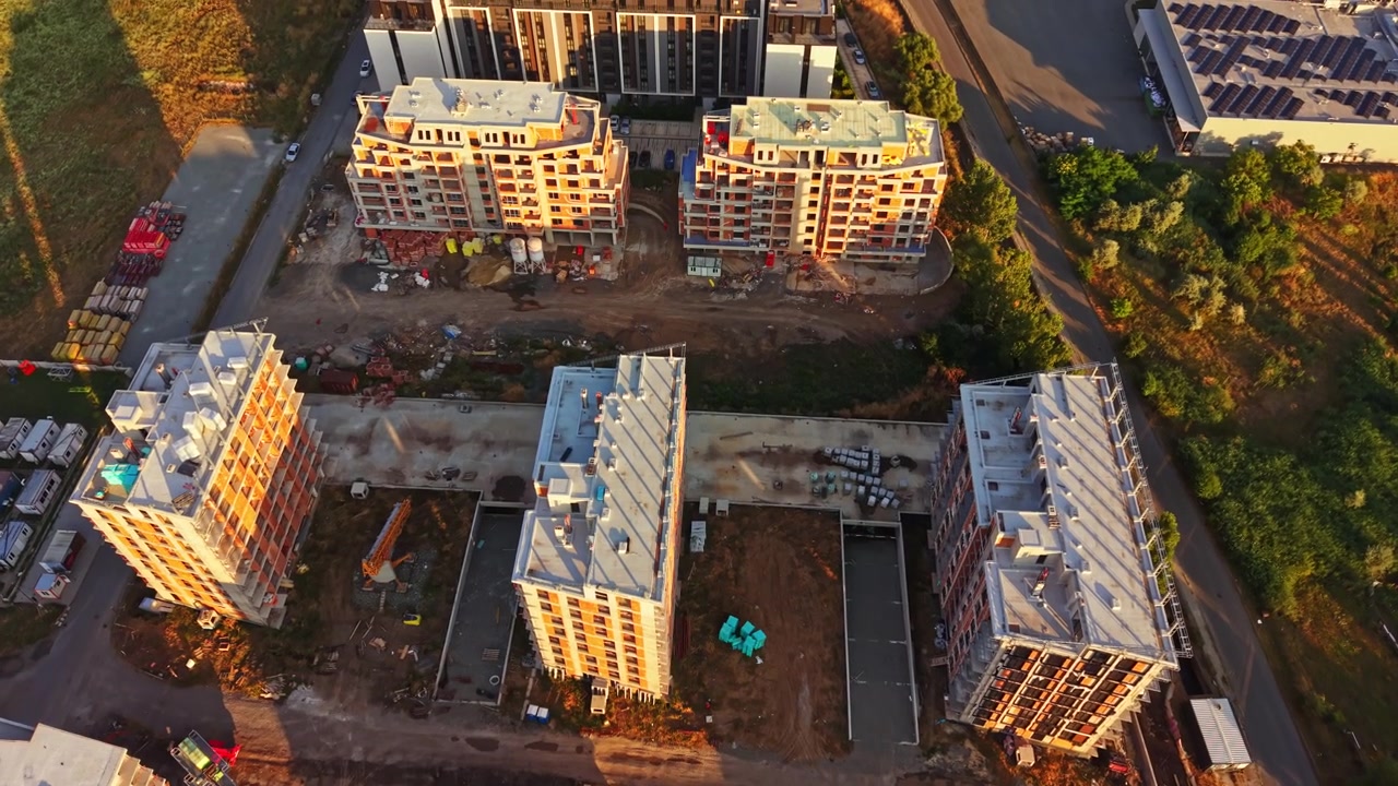 Construction of new buildings in a city area with cranes and equipment visible during early morning hours