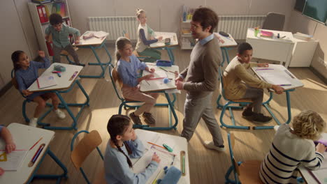 schoolteacher talking with pupils. students running from classroom for holidays