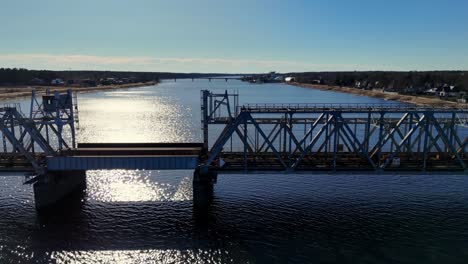 Aerial-view-of-a-long,-steel-railway-bridge-spanning-a-wide,-blue-river-Daugava