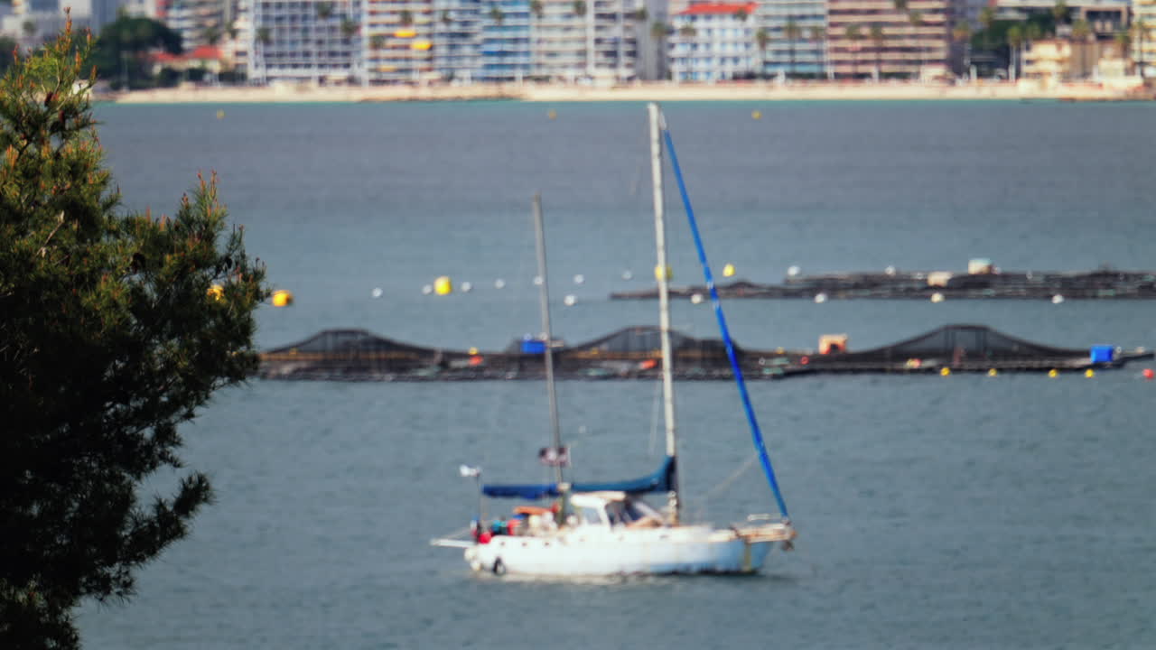 Blurred view of a white boat docked on the sea with the buildings and the mountains on the background