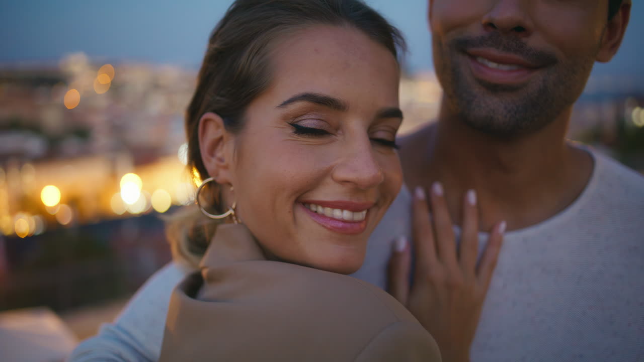 retrato de una novia sonriente posando con un hombre feliz en la vista de las luces de la ciudad por la noche.