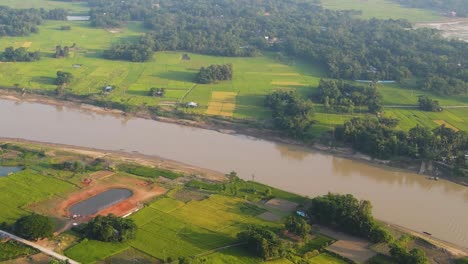 aerial view of surma river running through rural green countryside fields in sylhet, bangladesh