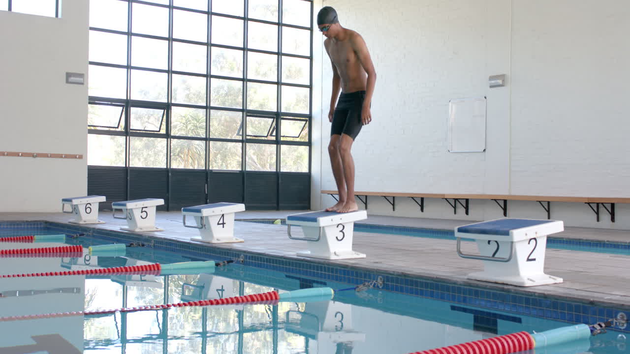 젊은 남성 남성 운동 선수 수영 선수 가 실내 수영장 에서 다이빙 을 준비 하고 있다