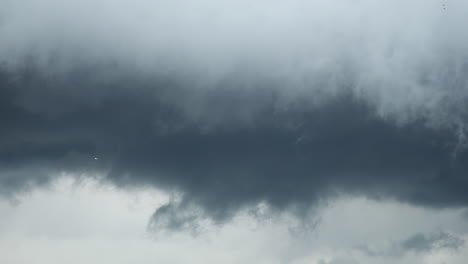 dark gloomy storm clouds in the sky and some flying birds