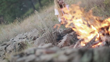 young woman sitting near campfire