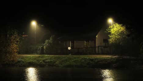 dark autumn night with man running past house under glowing streetlights latvia