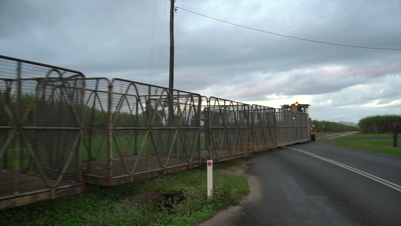 tren de caña de azúcar amarillo vacío conduciendo por el cruce de carreteras