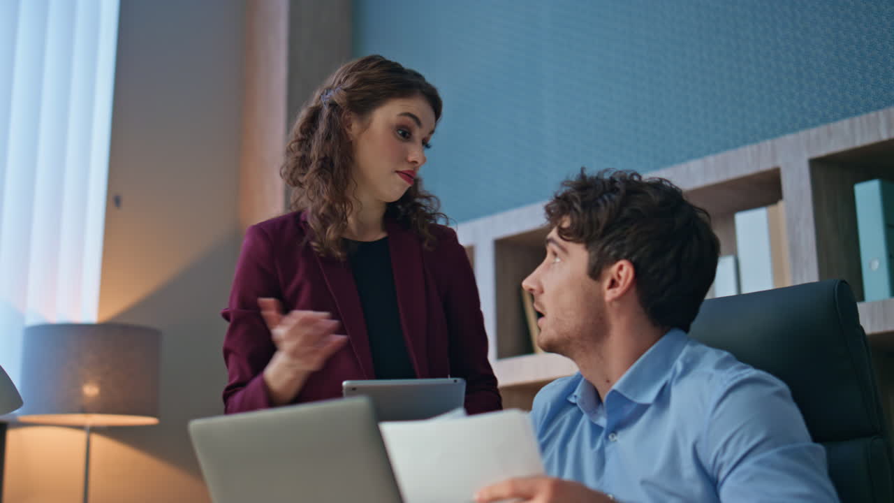 Two coworkers examining papers working together in company office close up.