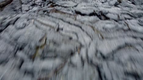 dynamic flight over a cooling field of black lava revealing a smoking volcano in iceland