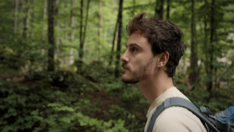 a young hiker walking on a path through the forest, using hiking poles and admireing the surroundings