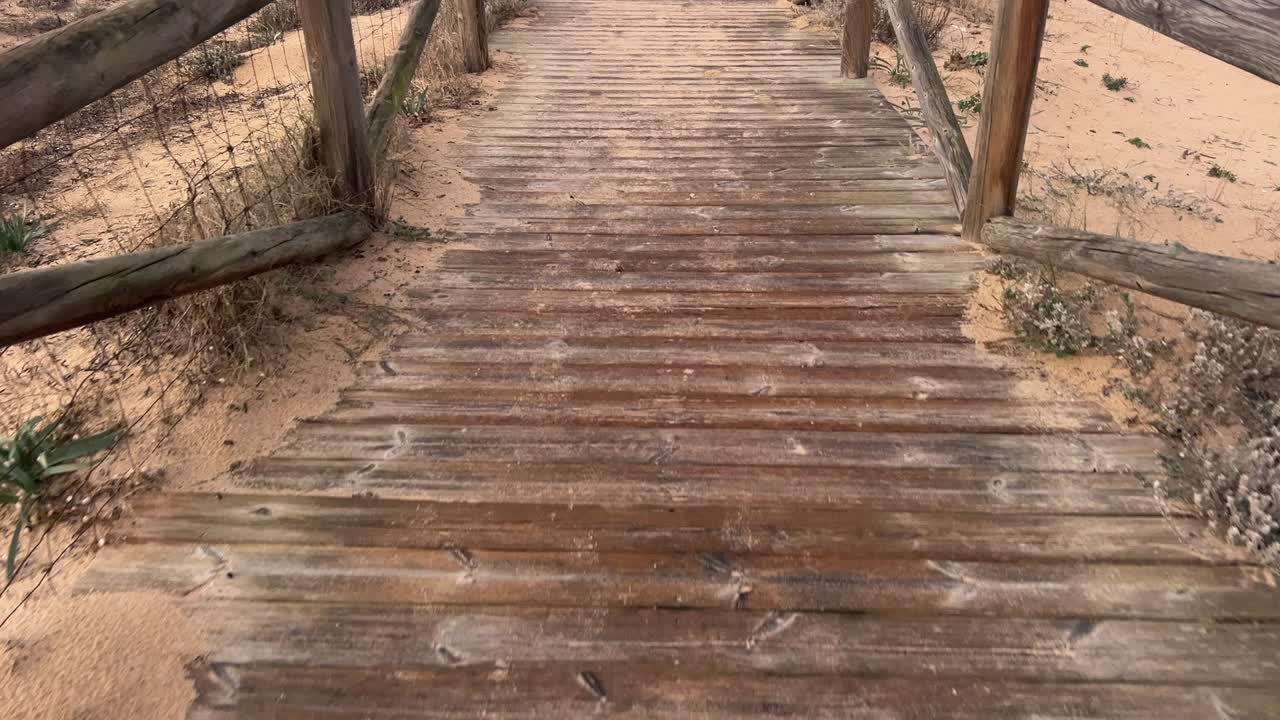 shot focusing on the beach path with wood and sand