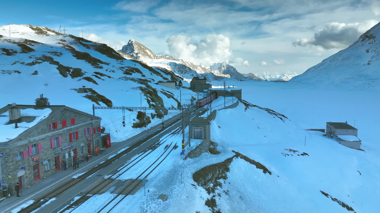 tren saliendo de un túnel y entrando en la estación de tren ospizio bernina en suiza