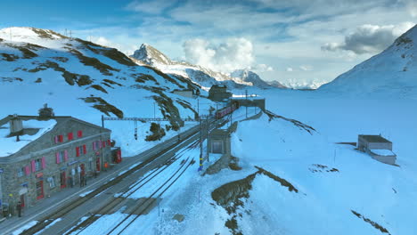 train exiting a tunnel and entering the ospizio bernina train station in switzerland