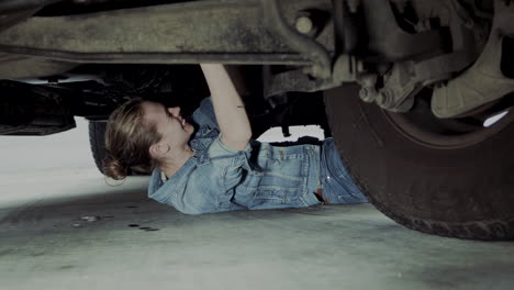 Woman-in-early-20s-checking-under-the-hood-of-a-truck-and-going-under-the-truck-to-find-and-fix-mechanical-problem