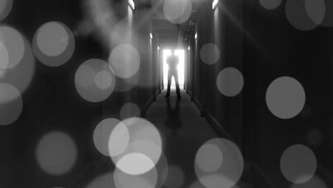 animation of grey bokeh light spots over scary figure backlit in doorway at end of dark corridor