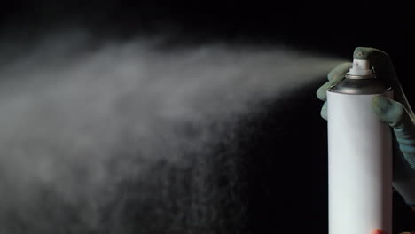 hand with a spray can sprays it on a black background