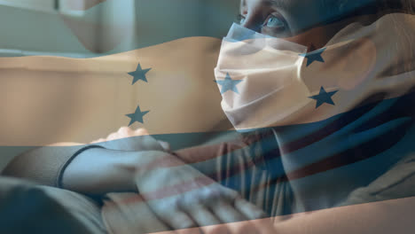 una mujer con una máscara en la cara ondeando la bandera de honduras