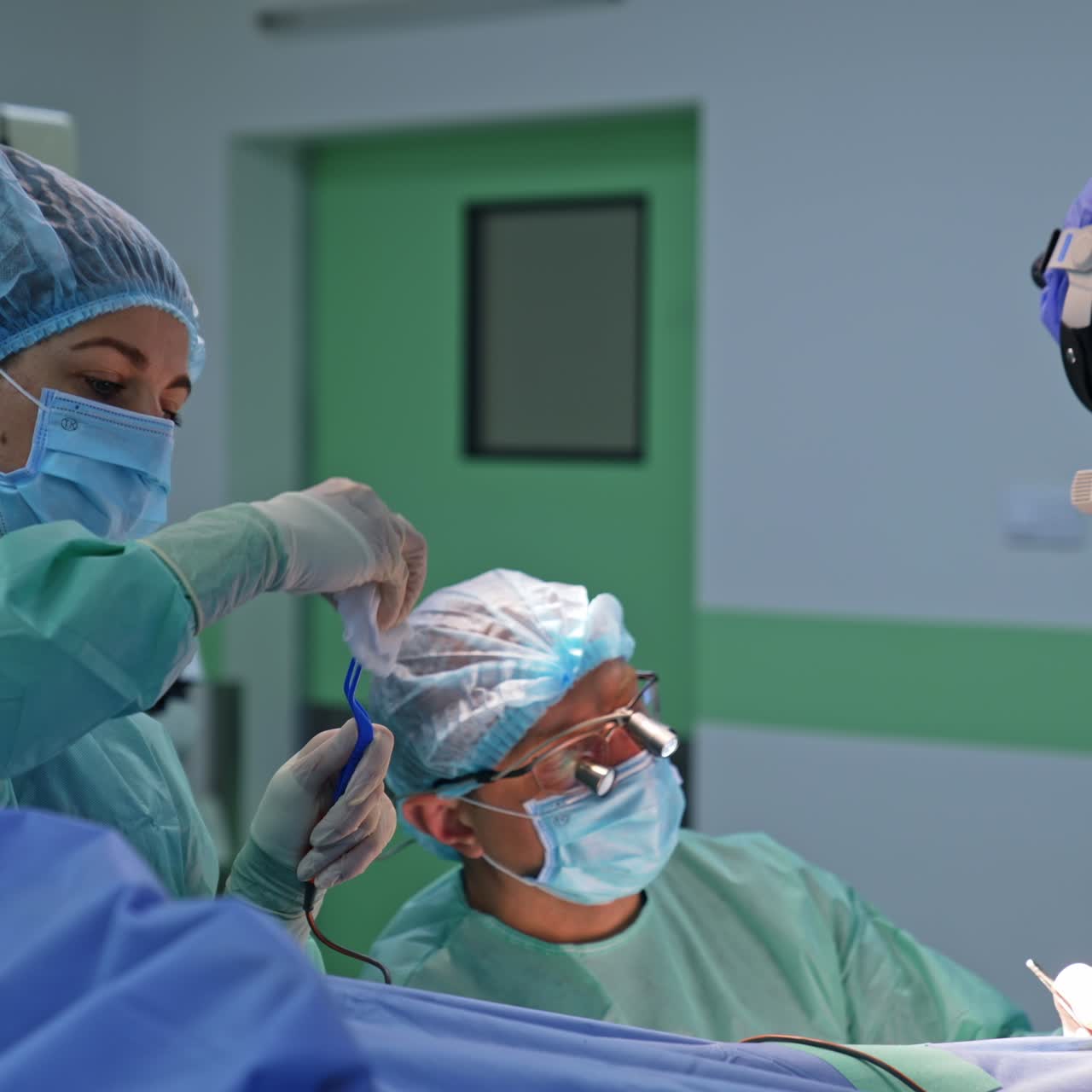Neurosurgery group of doctors cooperating at surgery. Nurse cleans the tool device and gives it to surgeons