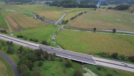 Vehículos-Que-Circulan-Por-La-Autopista-M1-Del-Pacífico-A-Lo-Largo-De-Los-Campos-Verdes-En-Nueva-Gales-Del-Sur,-Australia