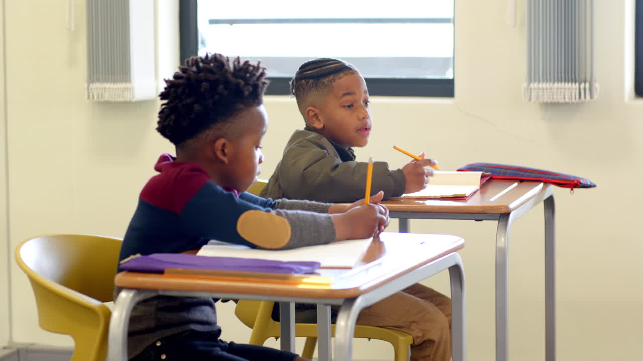In classroom, multiracial boys writing at desks, concentrating on schoolwork