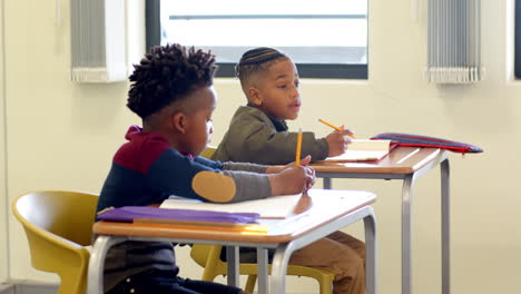 in classroom, multiracial boys writing at desks, concentrating on schoolwork