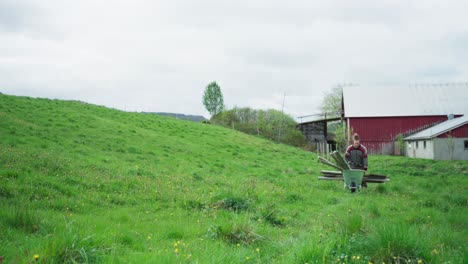 Man-Is-Working-At-The-Yard-Pulling-Wheelbarrow-Loaded-With-Poles