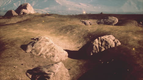 a scenic view of a grassy field with rocks and mountains in the background