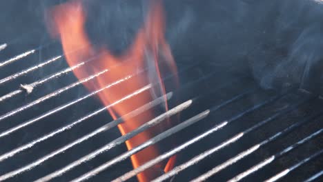 an open flame leaping through the grid when preparing a barbecue, close up