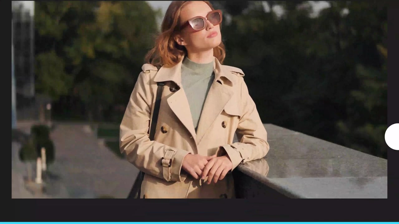 Stilfuld ung kvinde poserer i trenchcoat og solbriller.