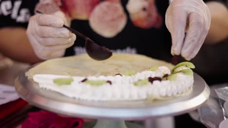 close-up of a person preparing a fruit and cream crepe