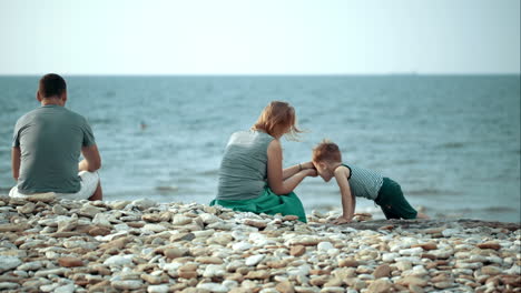 young parents and little son on pebble beach