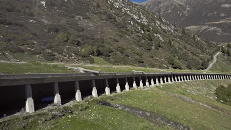 Seguimiento-De-La-Conducción-De-Automóviles-En-Un-Cobertizo-De-Rocas,-Hermoso-Y-Relajante-Paisaje-Soleado-De-Verano-De-Los-Alpes-Montañosos,-Kühtai,-Aéreo