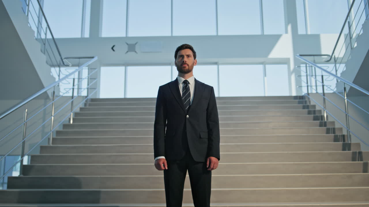 Serious executive standing confidently in office interior closeup. Businessman