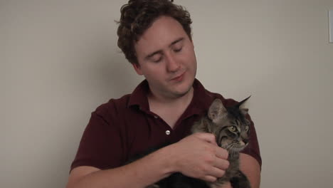 A-man-holds-and-pets-a-striped-cat