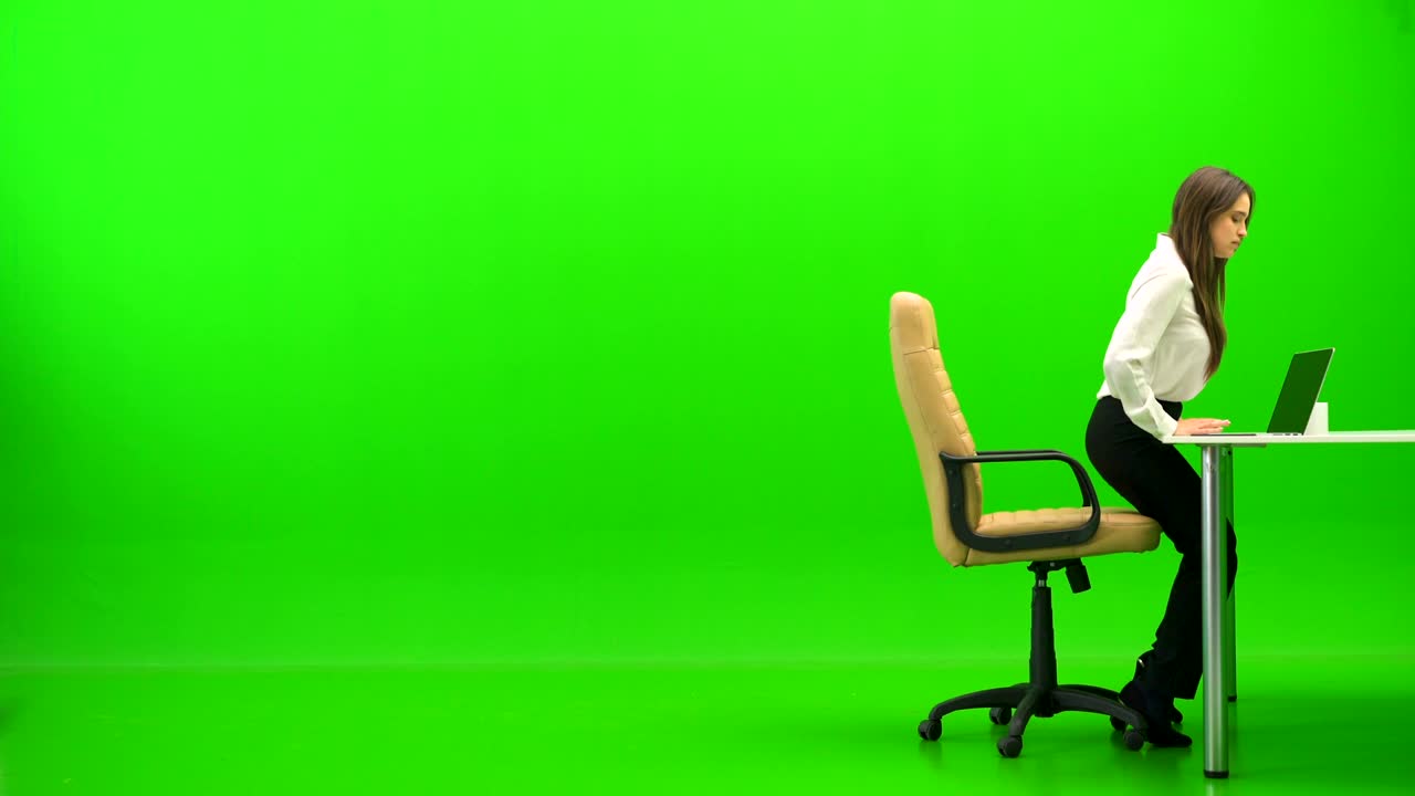 The woman working with at the table and phones on the green background