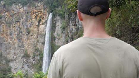 young caucasian man walking towards sipiso piso waterfall in north sumatra, indonesia