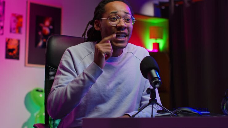 Un uomo di colore con dreadlocks e occhiali sta registrando un podcast nel suo studio casalingo