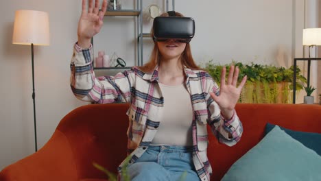 young woman use virtual reality headset glasses at home enjoying video concept moving hands in air
