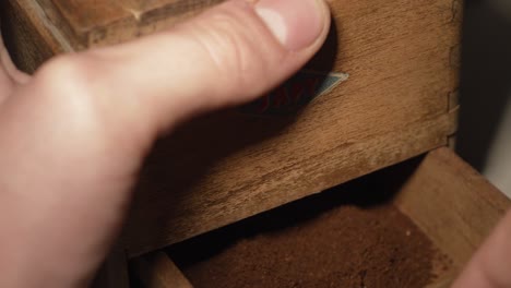 man opens an old coffee grinder with ground coffee japy grinder