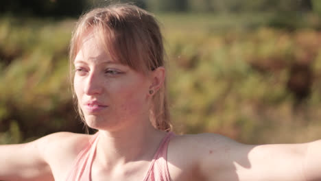 on a sunny day in the park, a young woman is seen performing the yoga pose known as the warrior pose or virabhadrasana