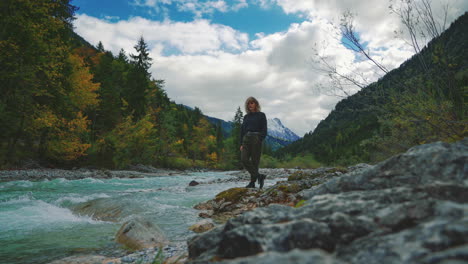 4k uhd cinemagraph - seamless video loop of a young brunette woman standing at a river near the scenic mountain lake hintersee in bavaria, germany